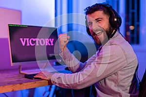 Millennial guy celebrates gaming victory, clenching fist
