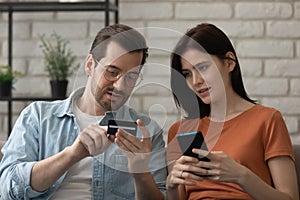 Millennial husband teaching wife to make cashless payment using phone