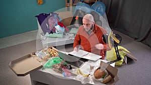 Millennial man anxious desperate worker annoyed work crumpling sheet of paper throw away working in messy home living