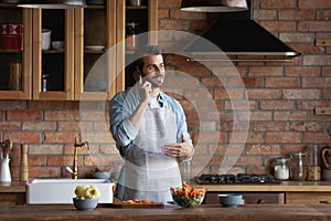 Millennial man cooking healthy salad talk on phone at kitchen