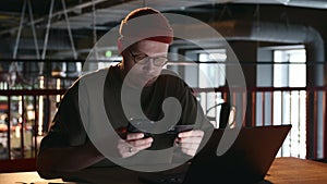 A millennial man enters information from a plastic bank card into his phone.