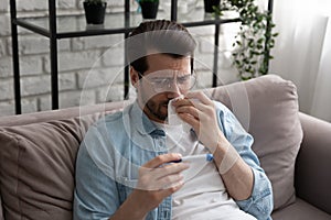 Millennial man feel ill wipe nose see fever on thermometer