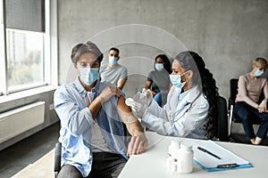 Millennial man getting intramuscular shot in shoulder, vaccination while pandemic