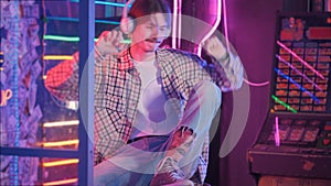 Millennial man in headphone dancing on disco. Neon Retro style