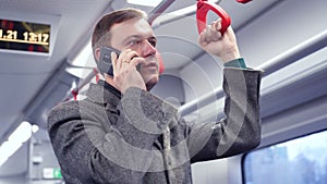 Millennial man making phone call in subway train. guy commuting to work on train using mobile phone