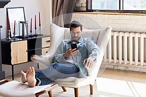 Millennial man relax in chair using cellphone device