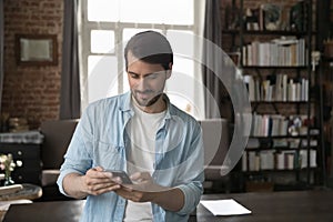 Man use smartphone standing in home office with modern smartphone photo