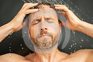 Millennial man washing hair in bath. Guy bathing shower head in bathtub. Face in foam in shower. Bathing man taking
