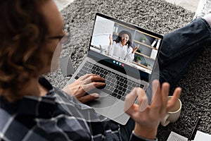 Millennial man watch online lesson, greets teacher and shows ok sign with hand at home