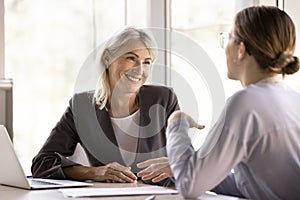 Millennial and middle-aged businesswomen having conversation in company office