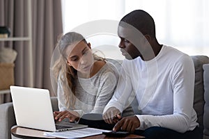 Millennial multiracial married couple calculating monthly family budget.