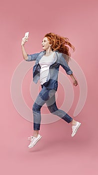 Millennial Redhead Girl Jumping And Using Phone,