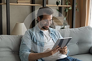 Guy rest on sofa with tablet enjoy weekend use internet