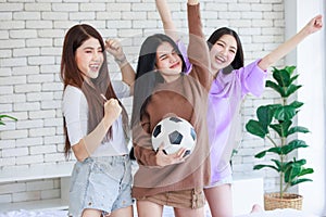 Millennial three Asian beautiful cheerful female girlfriends in casual outfit standing smiling holding football and hands fists up