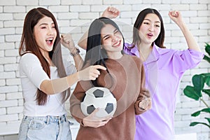 Millennial three Asian beautiful cheerful female girlfriends in casual outfit standing smiling holding football and hands fists up