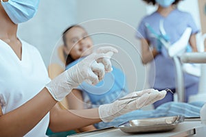 Millennial woman doctor in rubber gloves and protective mask processes dental instruments