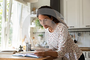 Millennial woman studying from home engaged in reading paper books