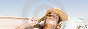 Millennial woman with sun hat asleep on hamoc against Summer sky