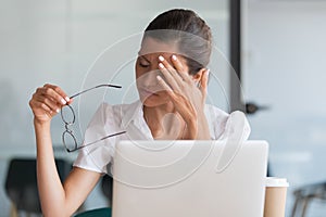 Millennial woman taking off glasses tired of computer work