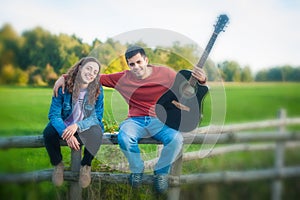 Millennials, cheerful young couple playing guitar and singing in nature