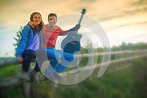 Millennials, cheerful young couple playing guitar and singing in nature