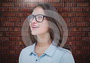 Millennials woman looking up against brick wall with flare