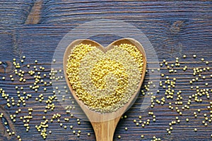Millet groats in heart shaped spoon. Copy space