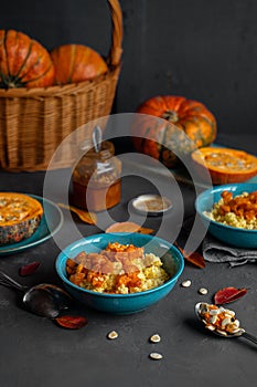 Millet porridge with pumpkin and honey served in blue bowls, raw pumpkins and seeds