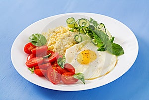 Millet porridge and tomato, cucumber salad and fried eggs.