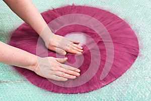 Milliner presses fibers on back side of hat layout