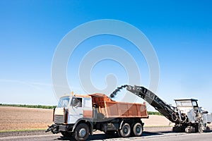 Milling machine removing crushed aphalt into dump truck