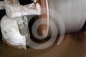 Millstone of industrial melanger grind cocoa in the process of making chocolate, blurry in motion