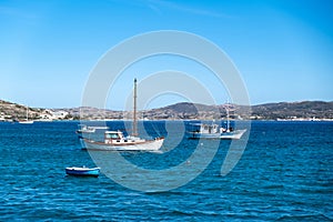 Milos Greek island, Cyclades. Fishing boat moored in open Aegean calm sea, blue sky background