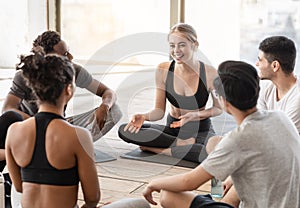 Milti-ethnic group of sporty people chatting and laughing before training in studio