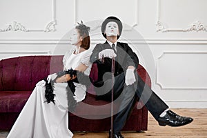 Mime artists, lady and gentleman sitting on sofa