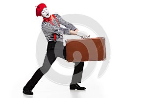 mime carrying heavy brown suitcase