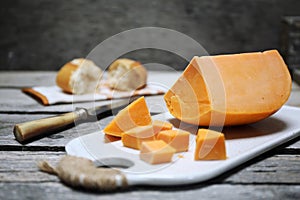 Mimolette cheese and baguette on cutting board