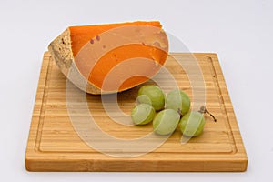 Mimolette cheese with grapes on a plate