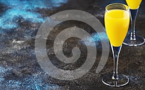 Mimosa alcohol cocktail with orange juice and dry champagne or sparkling wine in glasses, blue background, copy space