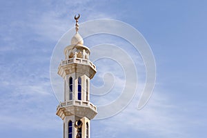 Minaret of the mosque against blue sky with wispy clouds in Abu Dhabi, UAE