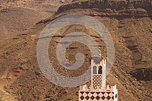  minaret tower against rugged mountain wall in atlas mountains - Morocco