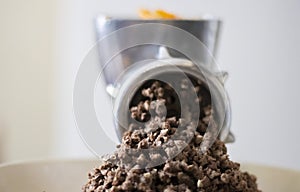 Minced meat in a manual mechanical meat grinder. Fresh boiled meat is ground with an old metal meat grinder, close-up in the