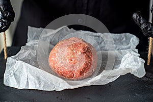 Minced meat on paper, stone tray, black gloves