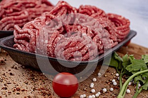 Minced meat in a tray with tomatoes, parsley and pepper