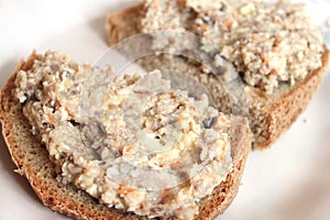 Mincemeat of herring on a slice of brown bread on white background close up view