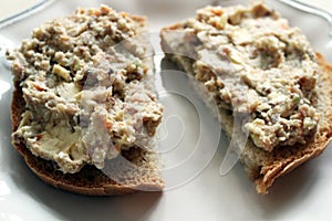 Mincemeat of herring on a slice of brown bread on white background close up view