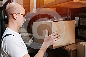 Mind absent male warehouse worker placing a box on the shelf