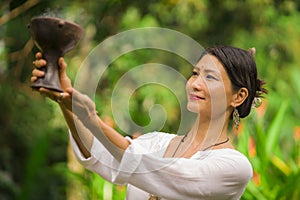 Mind and body connection - beautiful and happy healer Asian woman holding incense cup doing ritual traditional healing dance at