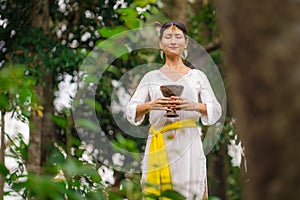 Mind and body connection - beautiful and happy healer Asian woman holding incense cup doing ritual traditional healing dance at