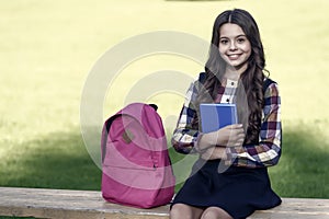 For mind that is eager to learn. Happy kid hold book sitting on bench. School library. Lending library. Bibliotheca